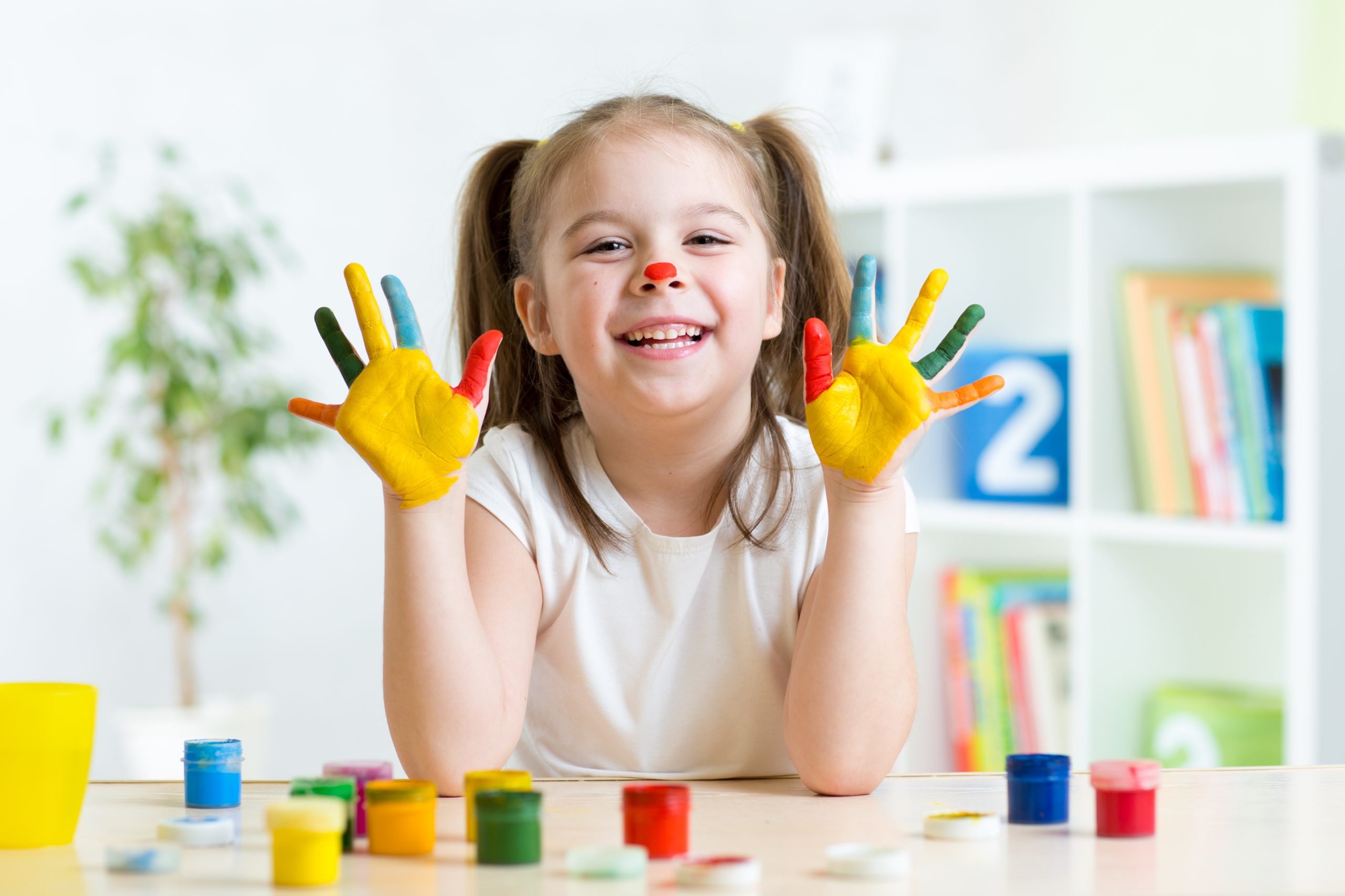 Girl having fun, her palms covered with paint